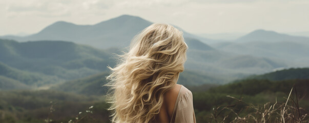 Woman with long wavy blond hairs with nature in background.  Dense long blonde hair rear view