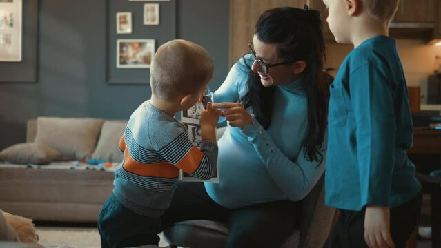 Pregnant adult shows children an ultrasound of upcoming child