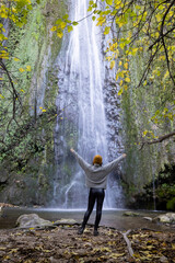 Young girl admiring waterfall in autumn - 692113130