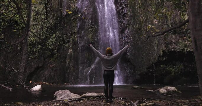Young girl admiring waterfall in autumn. Slow motion 4K DCI.
