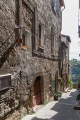 old houses on narrow downhill lane at medieval hilltop village, Pitigliano, Italy