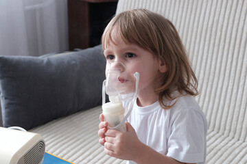 A little girl, a child of European appearance, blond hair, sits wearing an inhaler mask. Treatment...