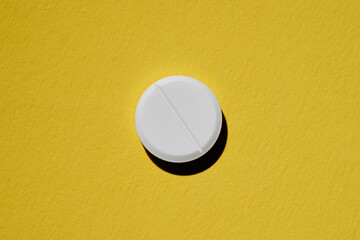 Pharmacy health care concept. Close up of white tablet on yellow background.
