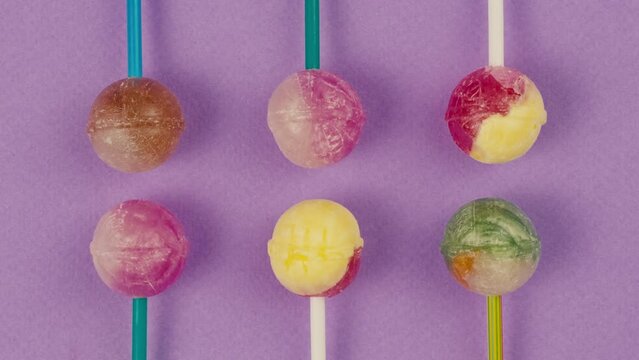 Sweet lollipops on color purple background zoom frame . Bright texture sugar candies close up top view. Composition of favorite children's summer sweets. Studio shot for shop, supermarket