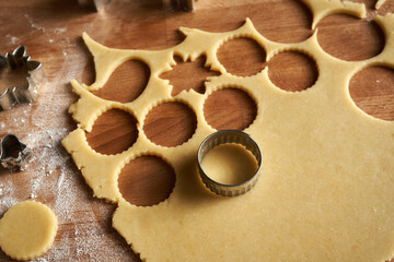 Cutting out circle shapes from rolled out dough to prepare Linzer Christmas cookies