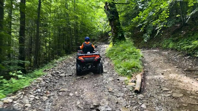 Man riding on quad bike in mountain. Tourist on quad bike on beautiful nature background. People, leisure and vacation concept. Man on the ATV Quad Bike on the mountains road.