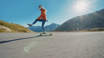 woman skateboarding and making tricks between the curves on a mountain pass. - obrazy, fototapety, plakaty
