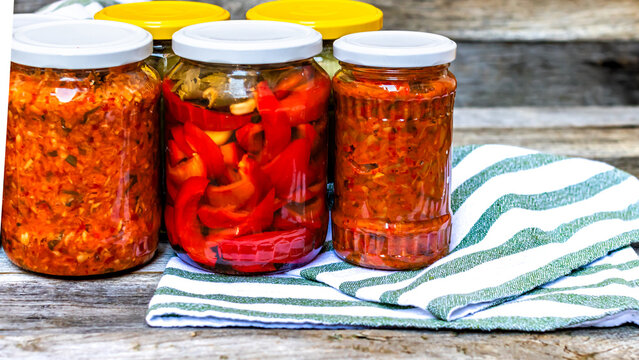 Jars with variety of canned vegetables and fruits, jars with zacusca. Preserved food concept in a rustic composition.