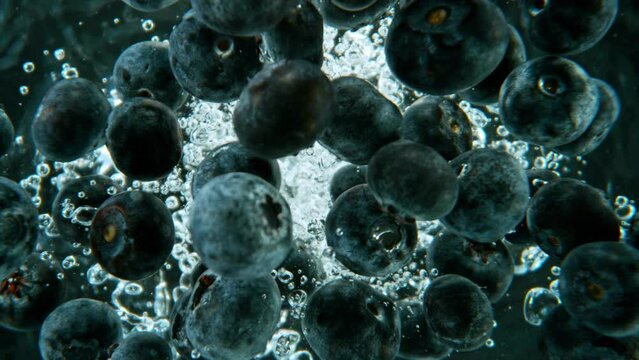 Super slow motion shot of falling blueberries into water, black background, underwater point of view. Filmed on high speed cinematic camera at 1000 fps.