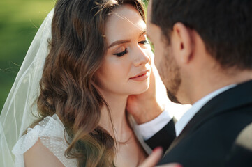 Beautiful wedding couple bonding and preparing to the kiss on the background of green grass. High...