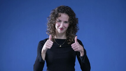 Person Giving Thumbs Up and OK sign with hands to Camera on Blue Background. Woman approving concept