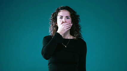 Surprised Woman Covering Mouth with Hand, Shocked by News on Teal Background