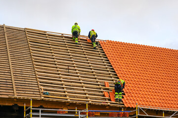Clay tile roof replacement, three workers laying new clay tile roof - obrazy, fototapety, plakaty