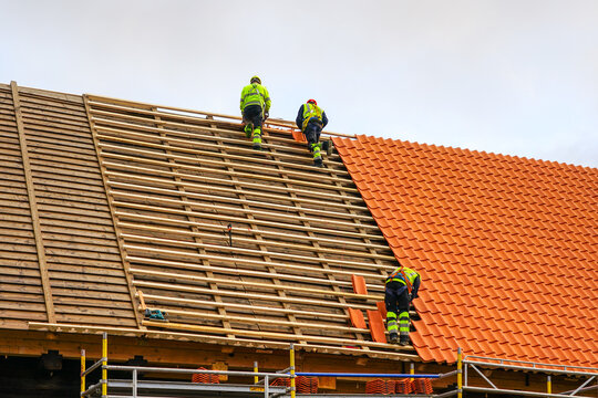 Clay tile roof replacement, three workers laying new clay tile roof