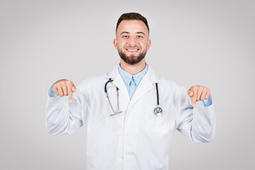 Smiling male doctor pointing down with both hands