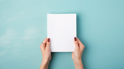 Bright and inviting portrayal of woman's hands presenting folded blank paper sheet or booklet, against pastel blue background, Focus on crispness of paper and clean, AI Generated