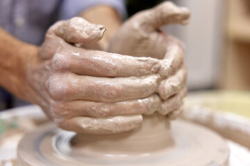Obraz na płótnie Canvas male hands making ceramic cup on pottery wheel, Close-up