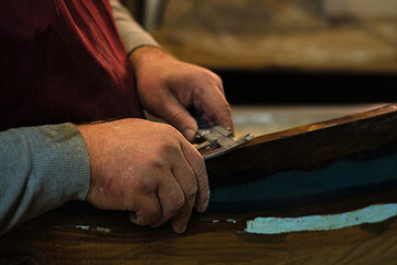 Artisan measuring with a tool; dedication, skill. Emphasizes the resurgence of traditional woodworking.