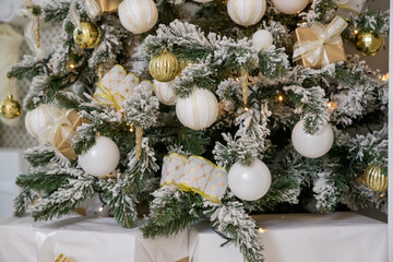 white modern christmas decoration. luxury interior with Christmas tree decorated, golden textile, golden presents,balls .festive tree decorated with garland, baubles, traditional celebration