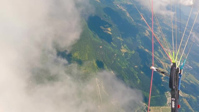 Paragliding pilot flying in fluffy storm clouds and turning fast in summer mountains adrenaline adventure extreme sport