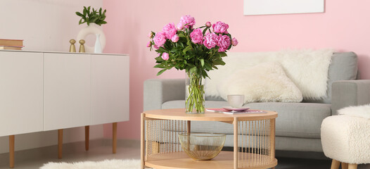 Vase with pink peonies on coffee table with couch in living room