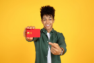Cheerful handsome young blank man holding red bank credit card