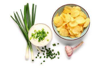 Bowl of tasty sour cream with sliced green onion and potato chips on white background