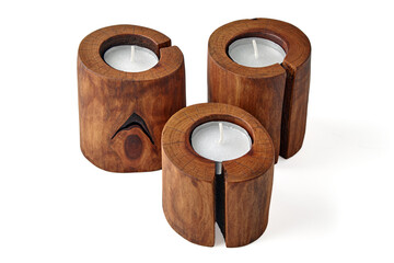 Three wooden candlesticks from a cut tree with a crack with candles isolated on a white background