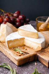 Wooden board with tasty Camembert cheese on table
