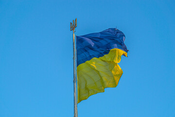 Ukraine flag large national symbol fluttering in blue sky. Large yellow blue Ukrainian state flag. National flag of Ukraine against blue sky. Detail of the national flag of Ukraine. Emblem of Ukraine