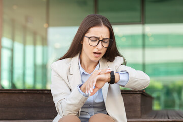 Obraz premium Sad stressed businesswoman checks watch with concerned expression, depicting urgency