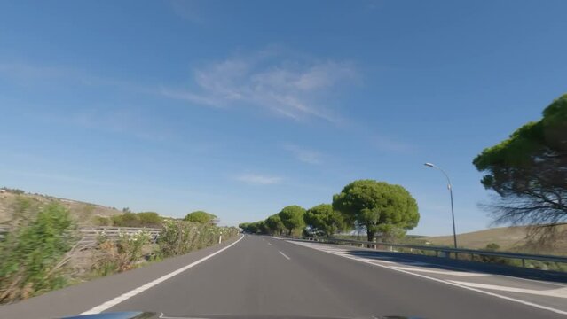 First person view, FPV, from dashcam of car driving in the beautiful Spanish countryside towards Seville, Andalusia, Spain, Europe. Road trip video in POV, with bright, sunny, blue sky