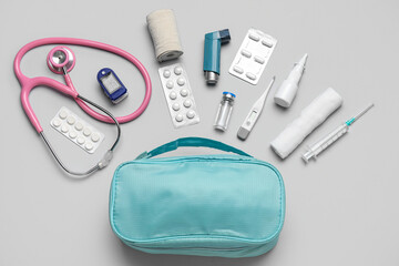 First aid kit and pills on grey background