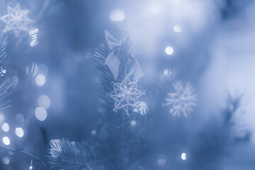 Straw snowflakes on christmas tree branch and bows in blurred background.