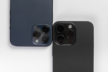 two smartphone cameras on a white background, , Iphone 15 pro max Black Titanium, iphone 12 pro max