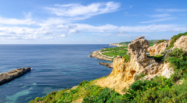 Mgarr, Malta - Panorama of Xatt l-Aħmar bay and cliffs in Malta at with beautiful colorful sky and golden rocks taken from near fort chambray © mantinilt
