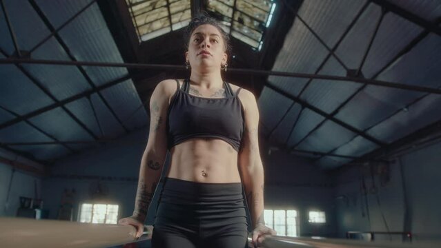 Front view of muscular female gymnast performing l-sits on parallel bars during gym workout