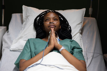 Female patient in hospital ward lies on bed prays looking at ceiling she is worried before surgery