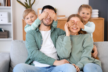 Little children covering eyes of their parents at home