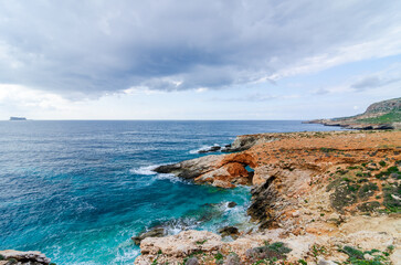 The Xaqqa Cliffs: Breathtaking view of the steep and rocky coastline and the ocean with crystal clear turquoise blue water. Climbing experience on the island of Malta. A paradise in europe.