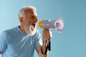 Angry mature 50s man with beard holding megaphone shouting, saying something looking away