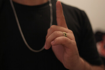 Man with a cord and a ring on his finger.