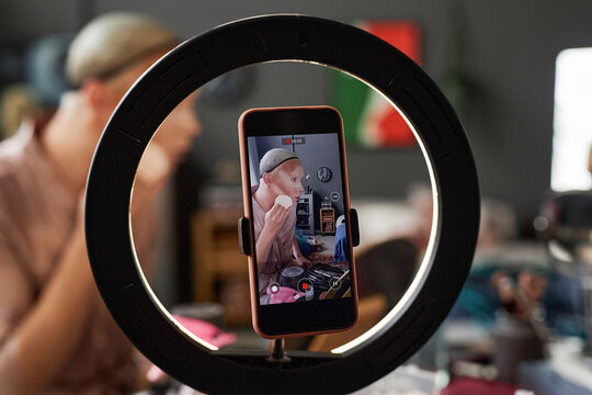 Close up of smartphone screen with young man filming stage makeup tutorial using ring light, copy space