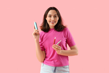 Young woman with electronic cigars on pink background