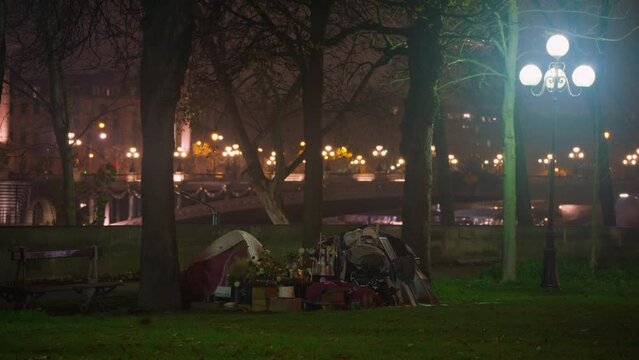 Homeless man lives in a tent in the center of Paris. Night city landscape with street lights. Nightlife in the center of Europe in the capital Paris. Night light decorations in center