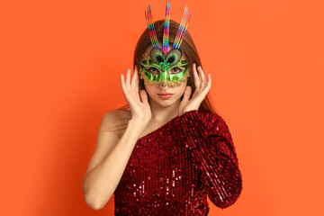 Beautiful young woman in carnival mask on orange background © Pixel-Shot