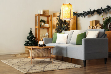 Interior of festive living room with grey sofa, glowing lamp and Christmas decorations