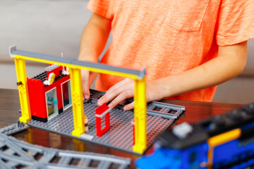 Child boy playing and building with colorful plastic bricks at the table