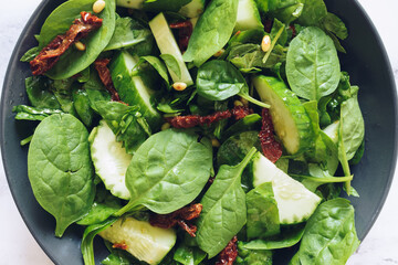 Healthy salad with spinach, cucumber, sun-dried tomatoes and pine nuts