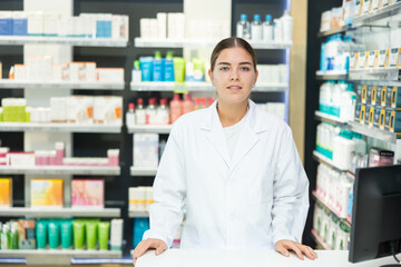 Young female pharmacist in medical uniform posing while working in pharmacy